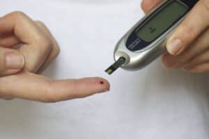 Colour image of someone testing blood sugar levels via a pin prick device